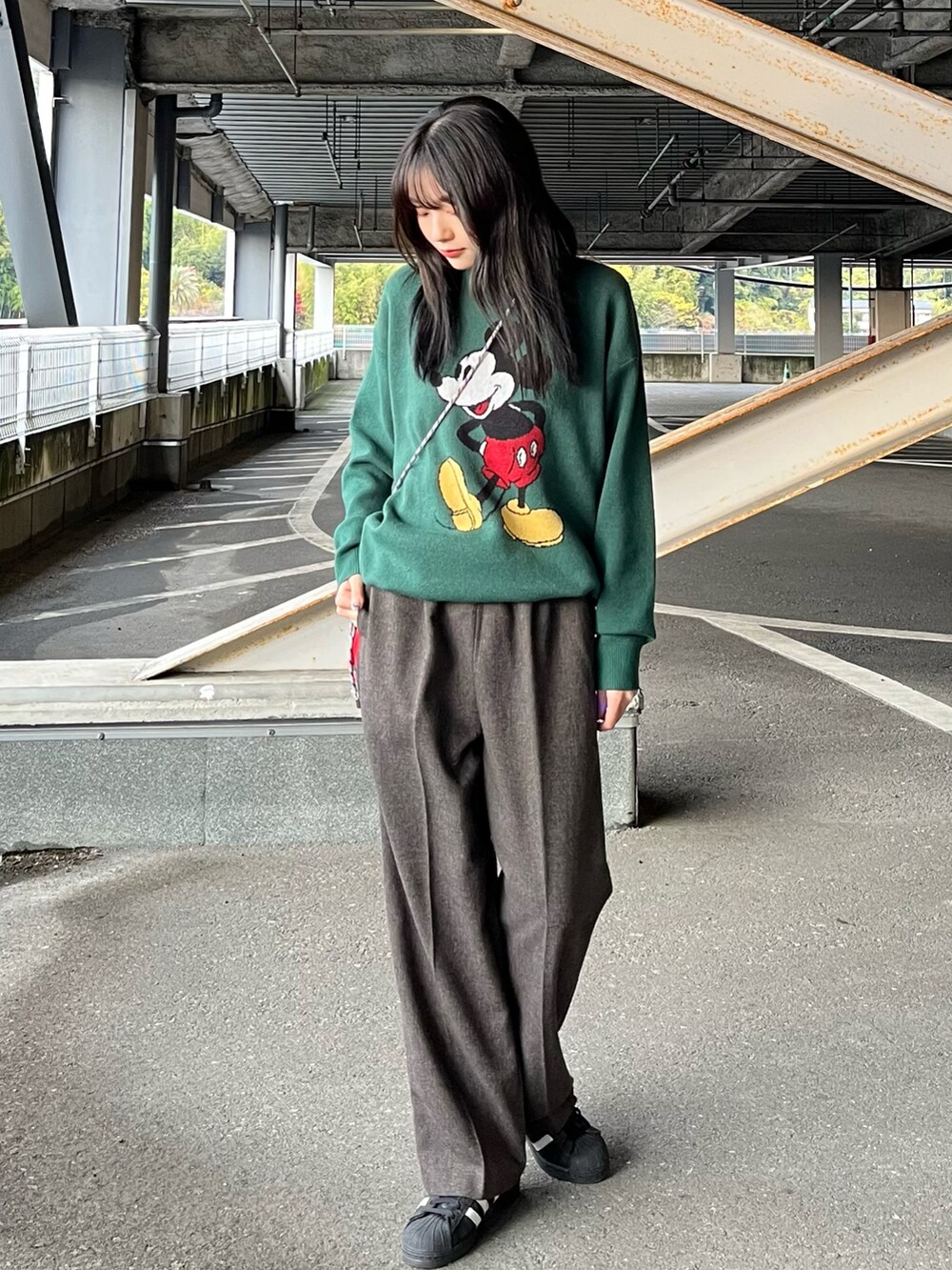 ブラック系のその他アウター、グリーン系のニット/セーター、ブラウン系のスラックスを着用したレディースの冬コーディネートの2枚目の写真