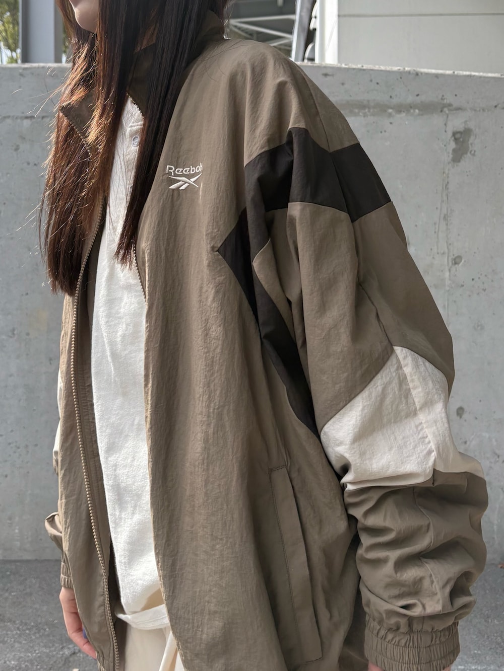 ベージュ系のナイロンジャケット、ベージュ系のチノパンツ、ベージュ系のショルダーバッグを着用したレディースの春コーディネートの3枚目の写真