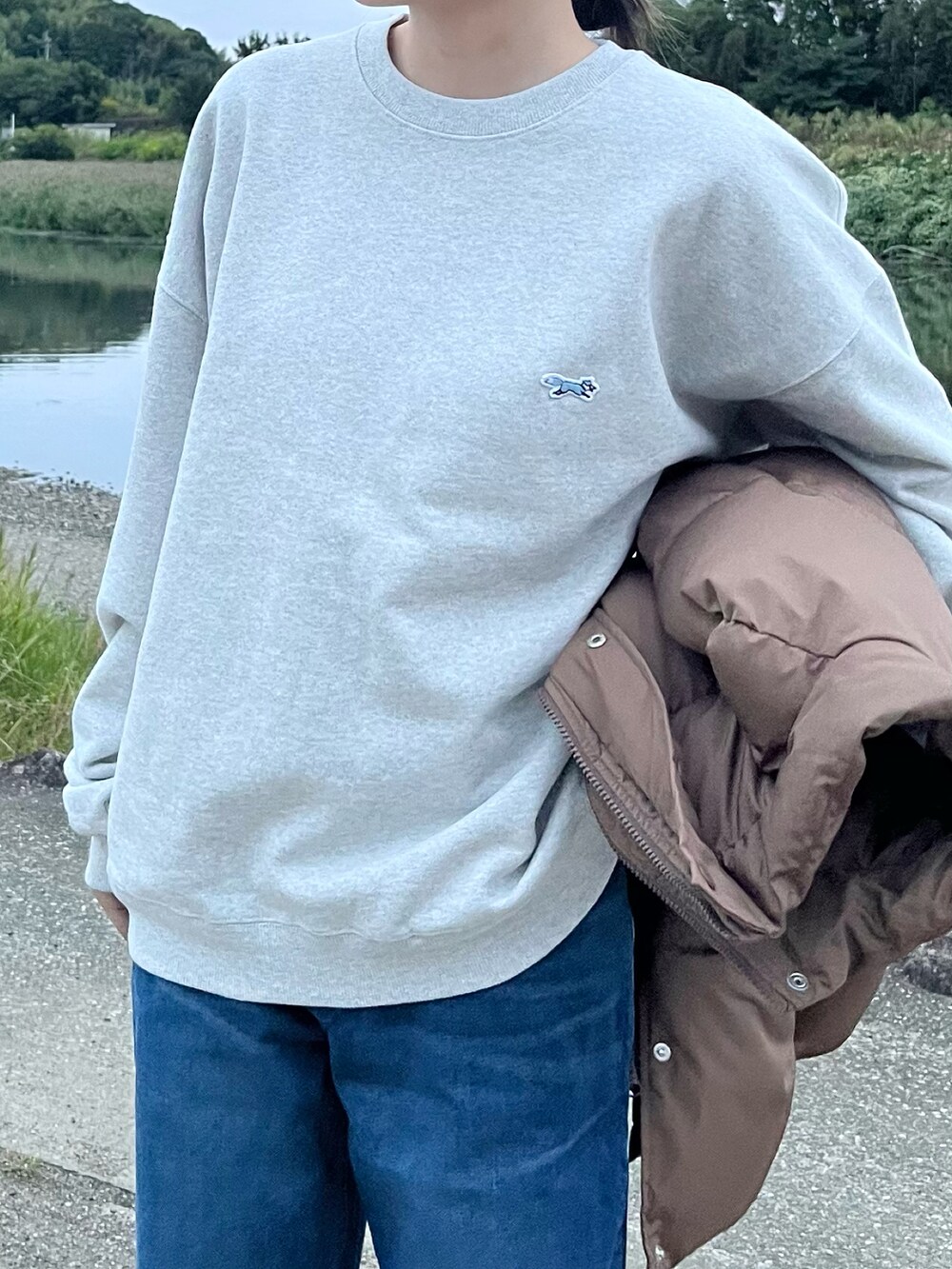 ブルー系のデニムパンツ、グレー系のスウェット、ブラウン系のベストを着用したレディースの秋コーディネートの3枚目の写真