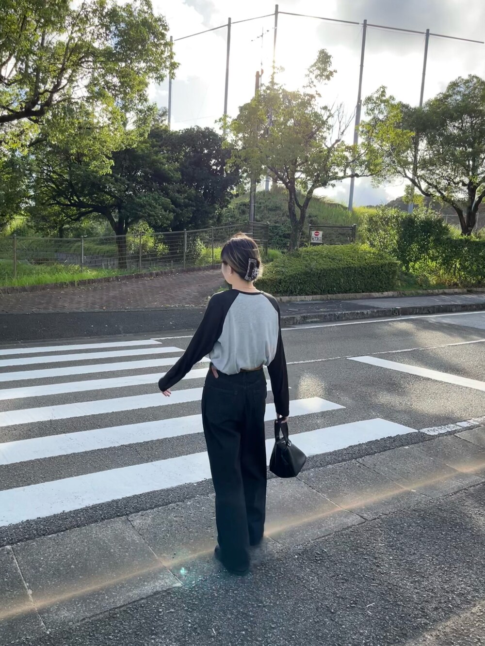 グレー系のTシャツ/カットソー、ブラック系のデニムパンツ、ホワイト系のスニーカーを着用したレディースの秋コーディネートの2枚目の写真