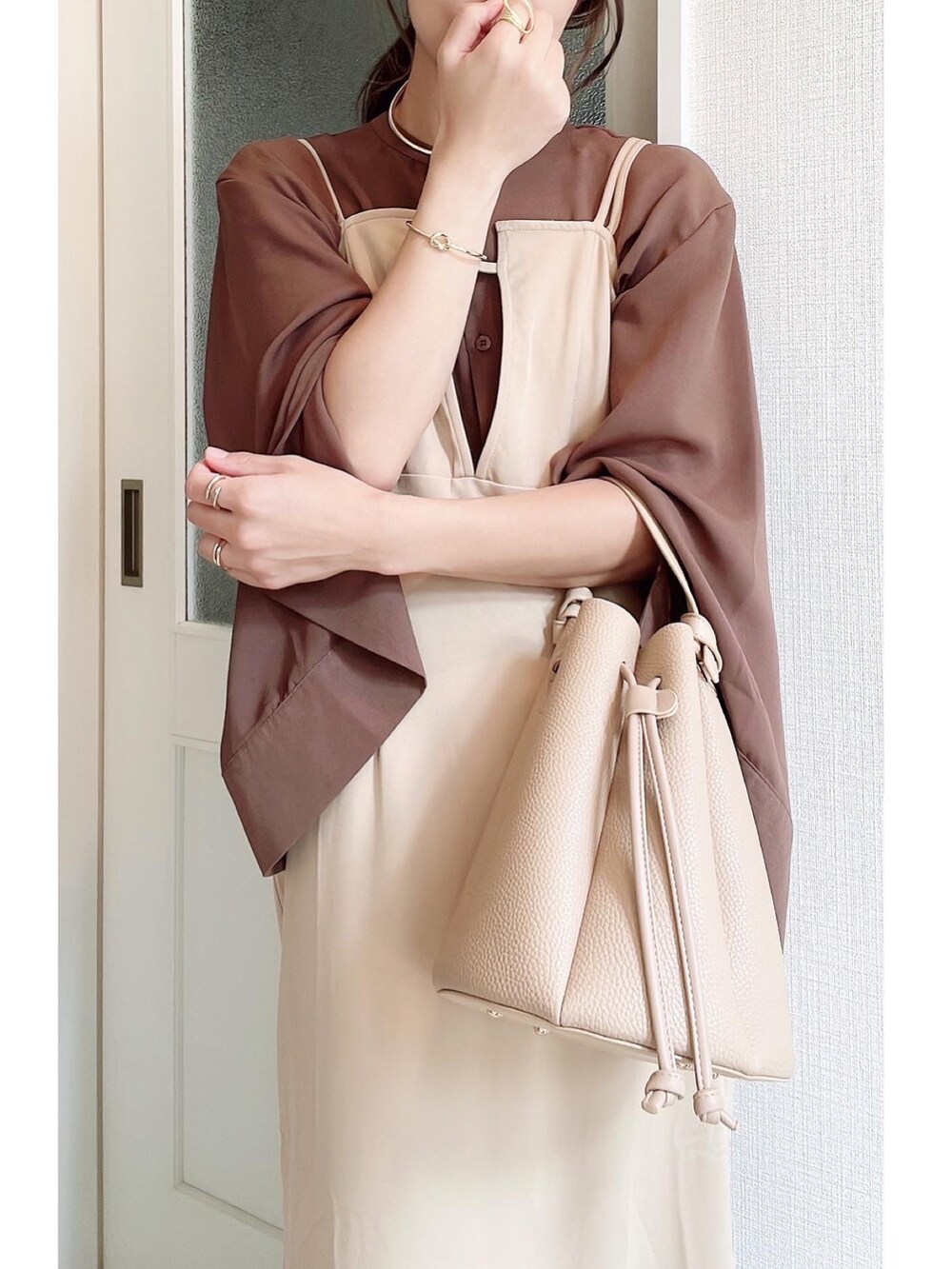 ベージュ系のハンドバッグ、ベージュ系のワンピース、ブラウン系のシャツ/ブラウスを着用したレディースの秋コーディネートの3枚目の写真