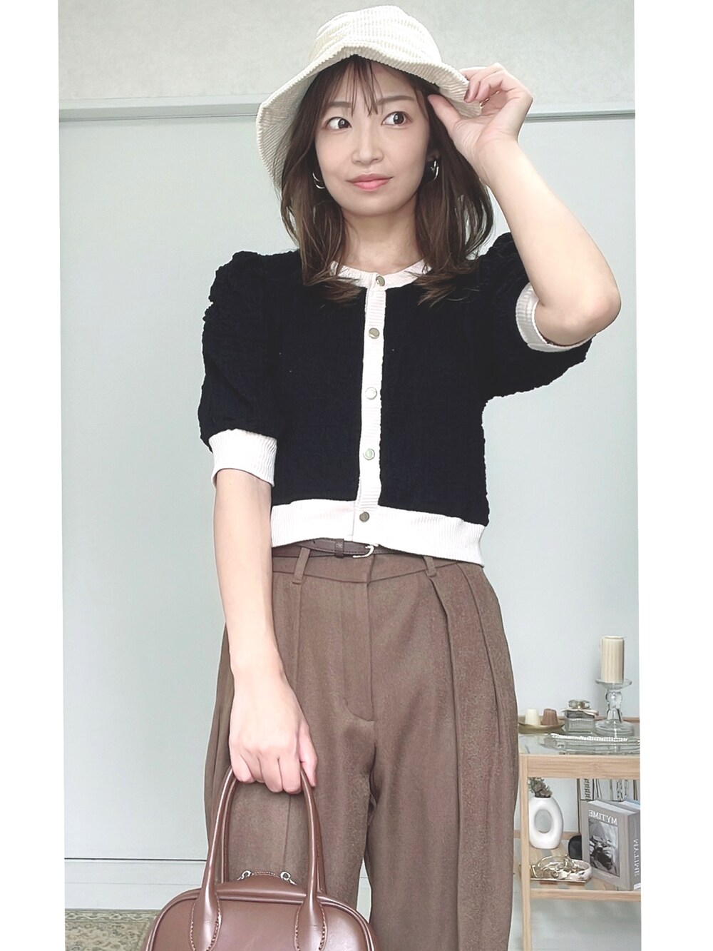 ブラック系のカーディガン/ボレロ、ブラウン系のハンドバッグ、ブラウン系のスラックスを着用したレディースの秋コーディネートの2枚目の写真