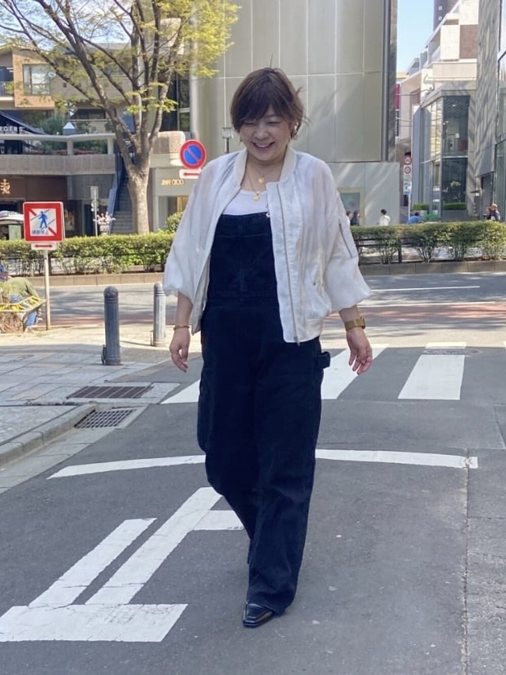 ホワイト系のミリタリージャケット、ブラック系のサロペット/オーバーオール、ホワイト系のタンクトップを着用したレディースの春コーディネートの3枚目の写真