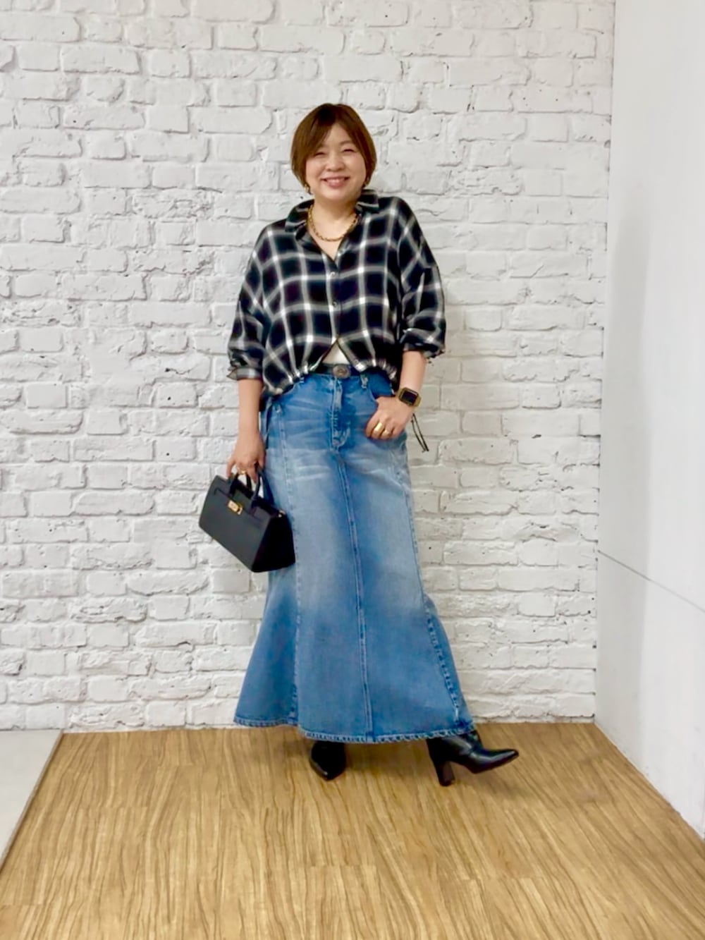 ブラック系のシャツ/ブラウス、ブルー系のデニムスカート、ブラック系のブーツを着用したレディースの秋コーディネートの3枚目の写真