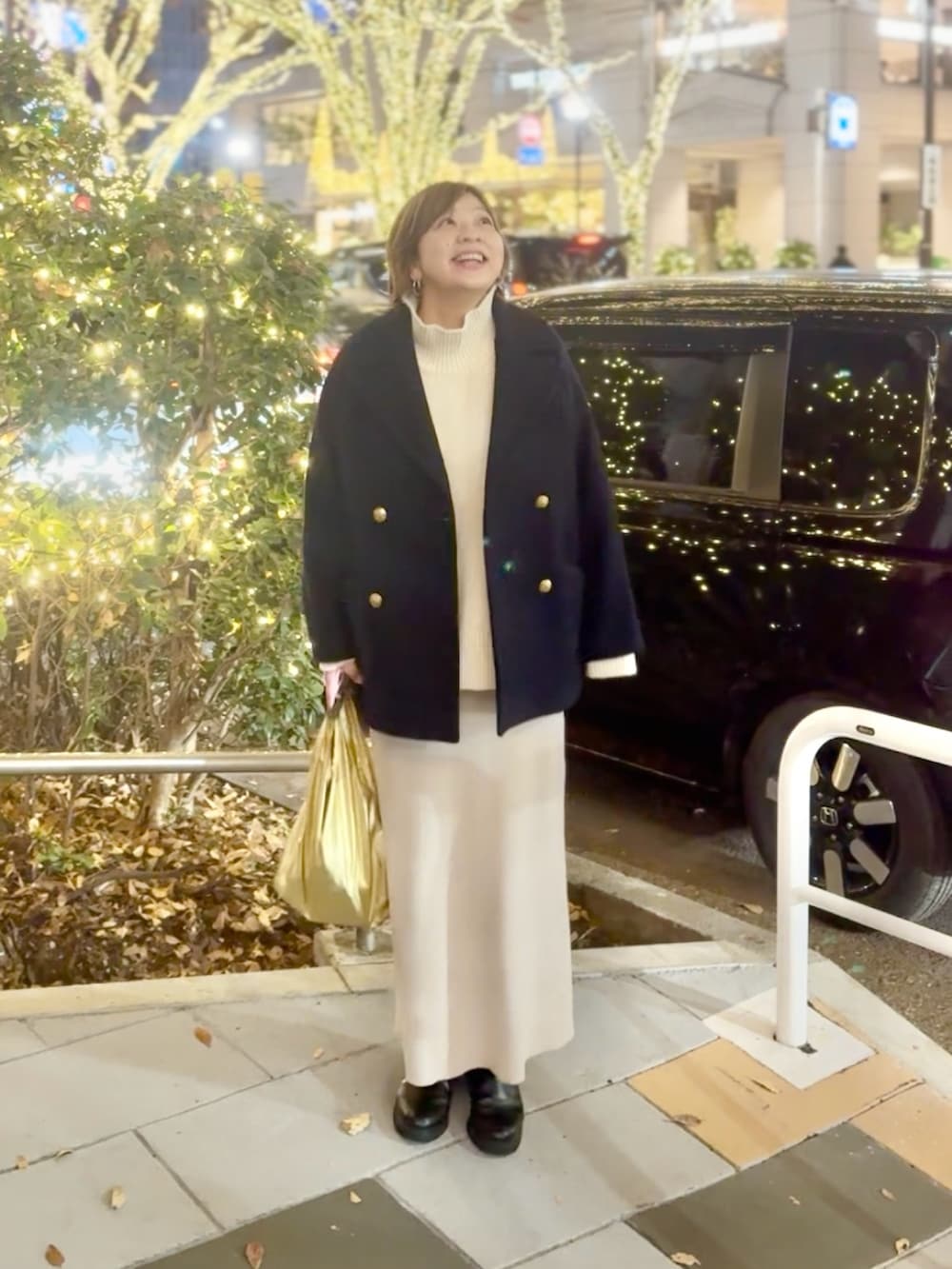 ホワイト系のニット/セーター、ホワイト系のスカート、ブラック系のブーツを着用したレディースの冬コーディネートの2枚目の写真