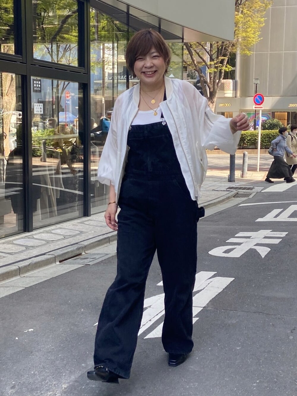 ホワイト系のミリタリージャケット、ブラック系のサロペット/オーバーオール、ホワイト系のタンクトップを着用したレディースの春コーディネートの2枚目の写真