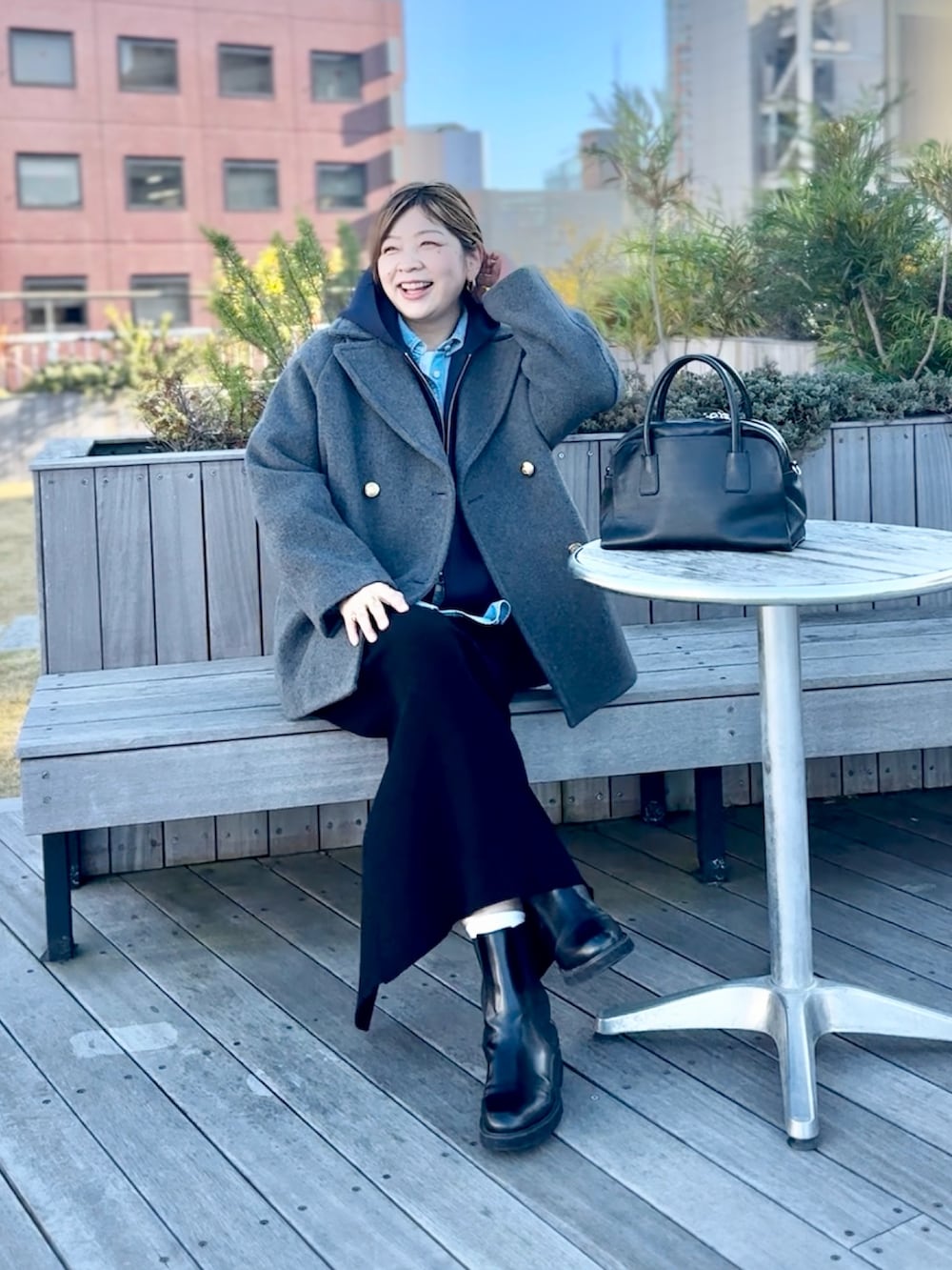 グレー系のピーコート、ブラック系のスカート、ブルー系のパーカーを着用したレディースの秋コーディネートの4枚目の写真