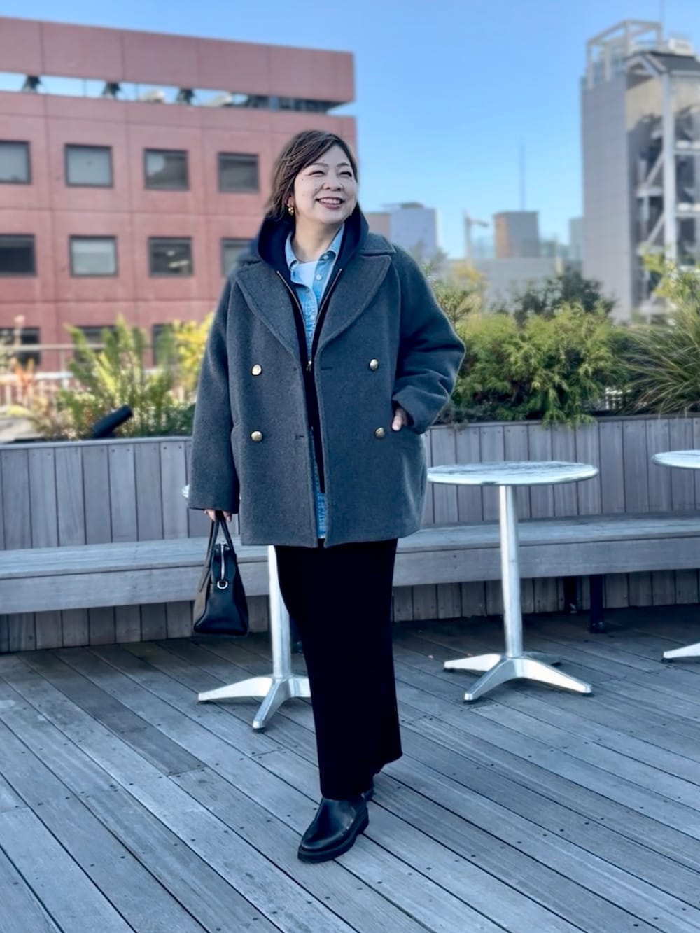 グレー系のピーコート、ブラック系のスカート、ブルー系のパーカーを着用したレディースの秋コーディネートの3枚目の写真