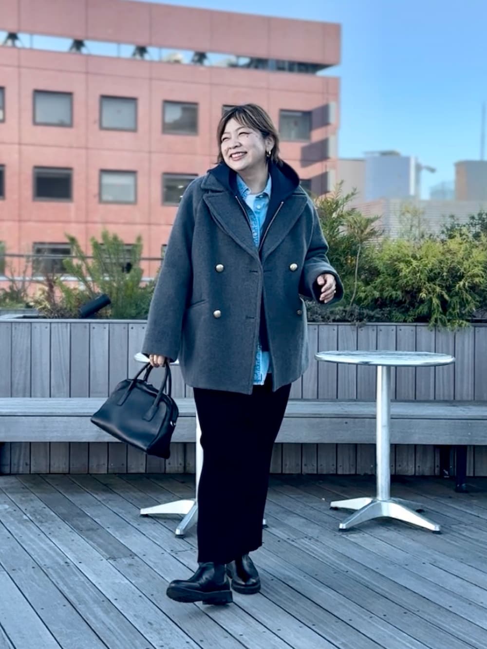 グレー系のピーコート、ブラック系のスカート、ブルー系のパーカーを着用したレディースの秋コーディネートの2枚目の写真