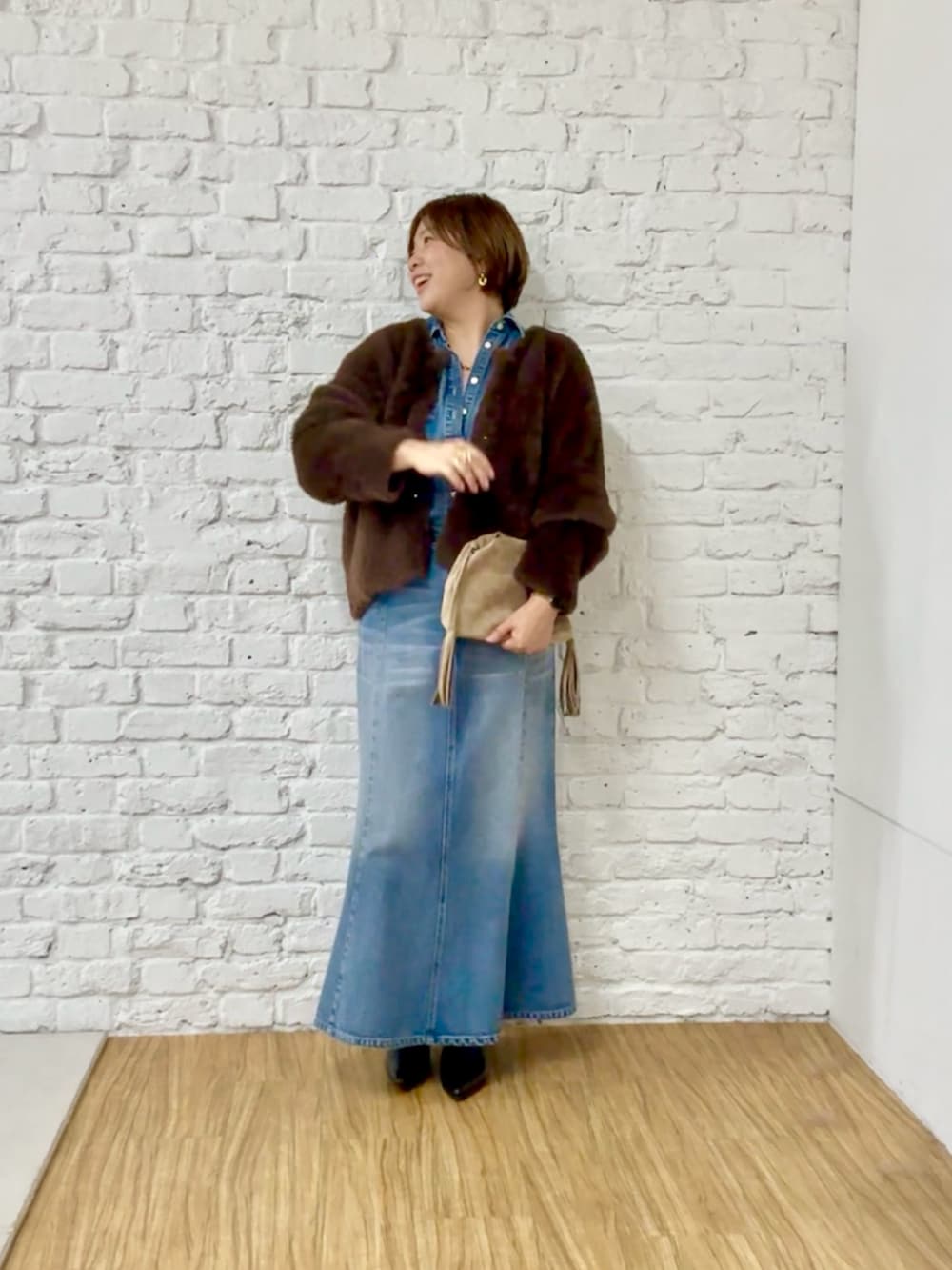 ブラウン系のカーディガン/ボレロ、ブルー系のシャツ/ブラウス、ブルー系のデニムスカートを着用したレディースの秋コーディネートの2枚目の写真