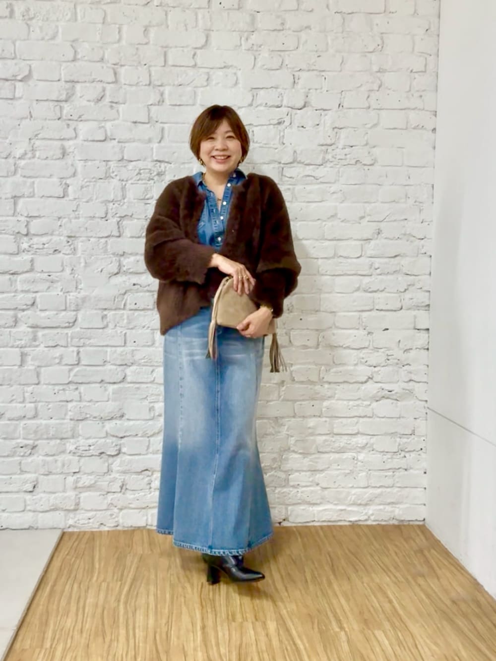 ブラウン系のカーディガン/ボレロ、ブルー系のシャツ/ブラウス、ブルー系のデニムスカートを着用したレディースの秋コーディネートの3枚目の写真
