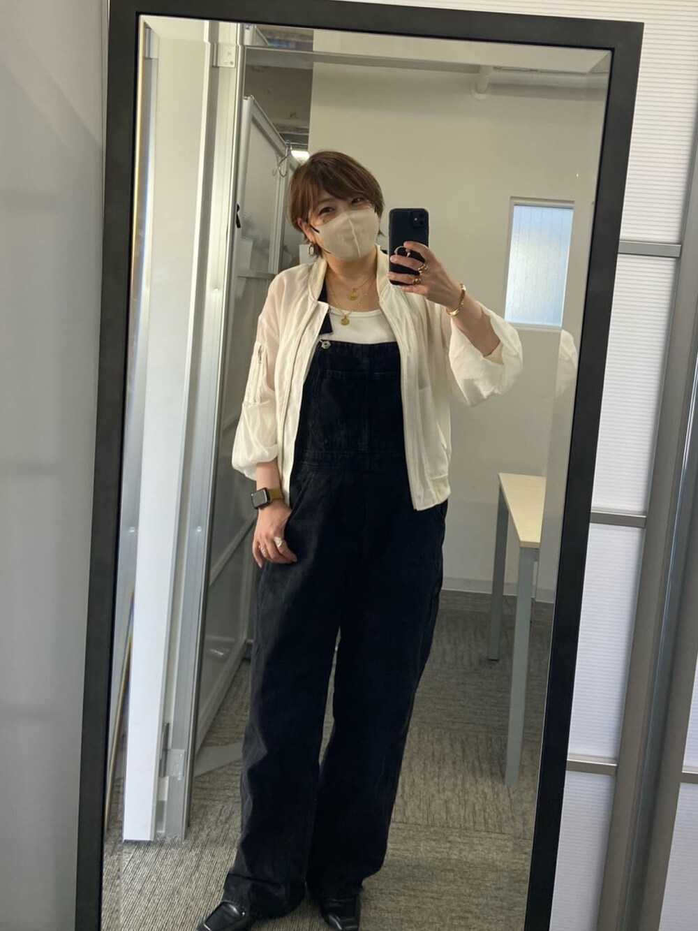 ホワイト系のミリタリージャケット、ブラック系のサロペット/オーバーオール、ホワイト系のタンクトップを着用したレディースの春コーディネートの4枚目の写真