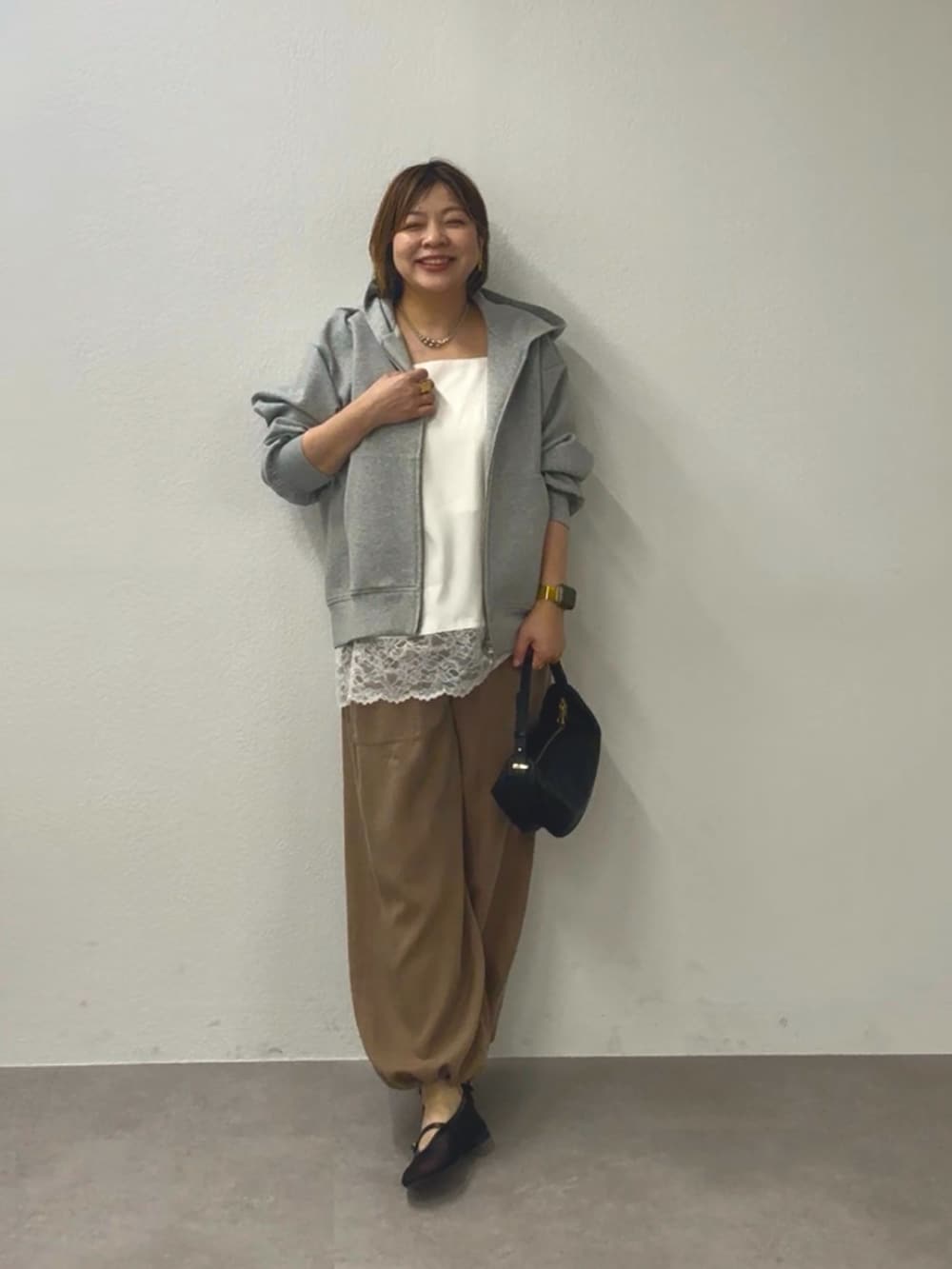 グレー系のパーカー、ホワイト系のキャミソール、ブラウン系のその他パンツを着用したレディースの冬コーディネートの2枚目の写真