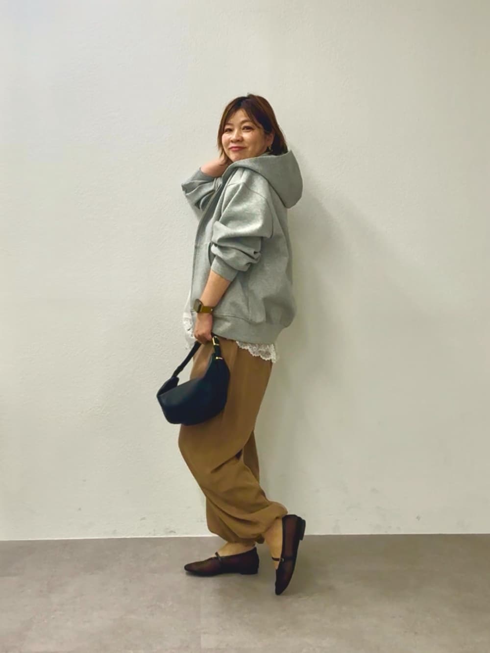 グレー系のパーカー、ホワイト系のキャミソール、ブラウン系のその他パンツを着用したレディースの冬コーディネートの3枚目の写真