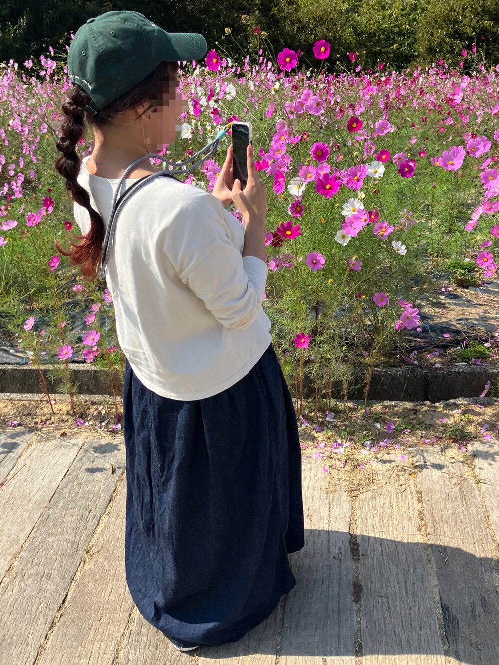 ホワイト系のTシャツ/カットソー、ブルー系のスカート、ピンク系のスニーカーを着用したレディースの秋コーディネートの2枚目の写真