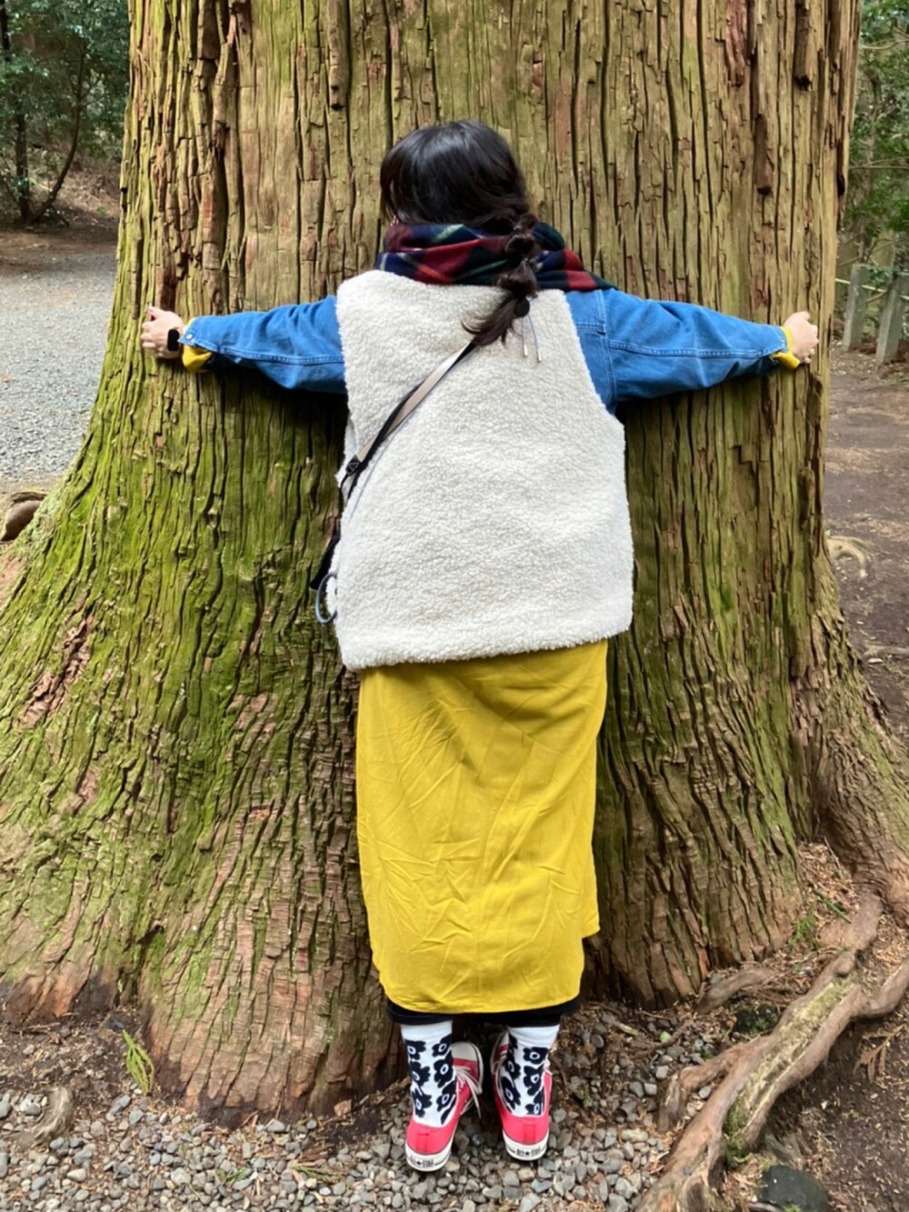 ホワイト系のベスト、イエロー系のワンピース、レッド系のスニーカーを着用したレディースの冬コーディネートの3枚目の写真