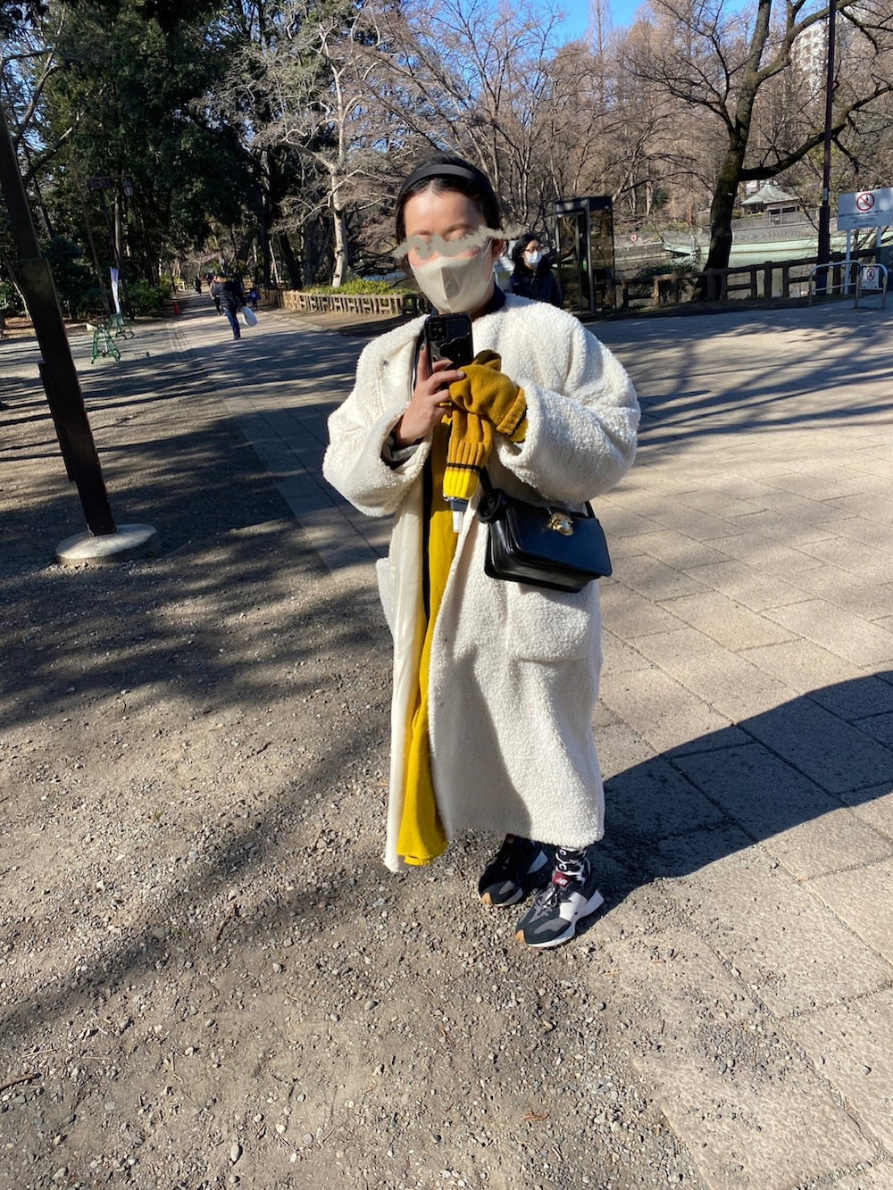 ホワイト系のノーカラーコート、イエロー系のワンピース、ブルー系のその他アウターを着用したレディースの冬コーディネートの2枚目の写真