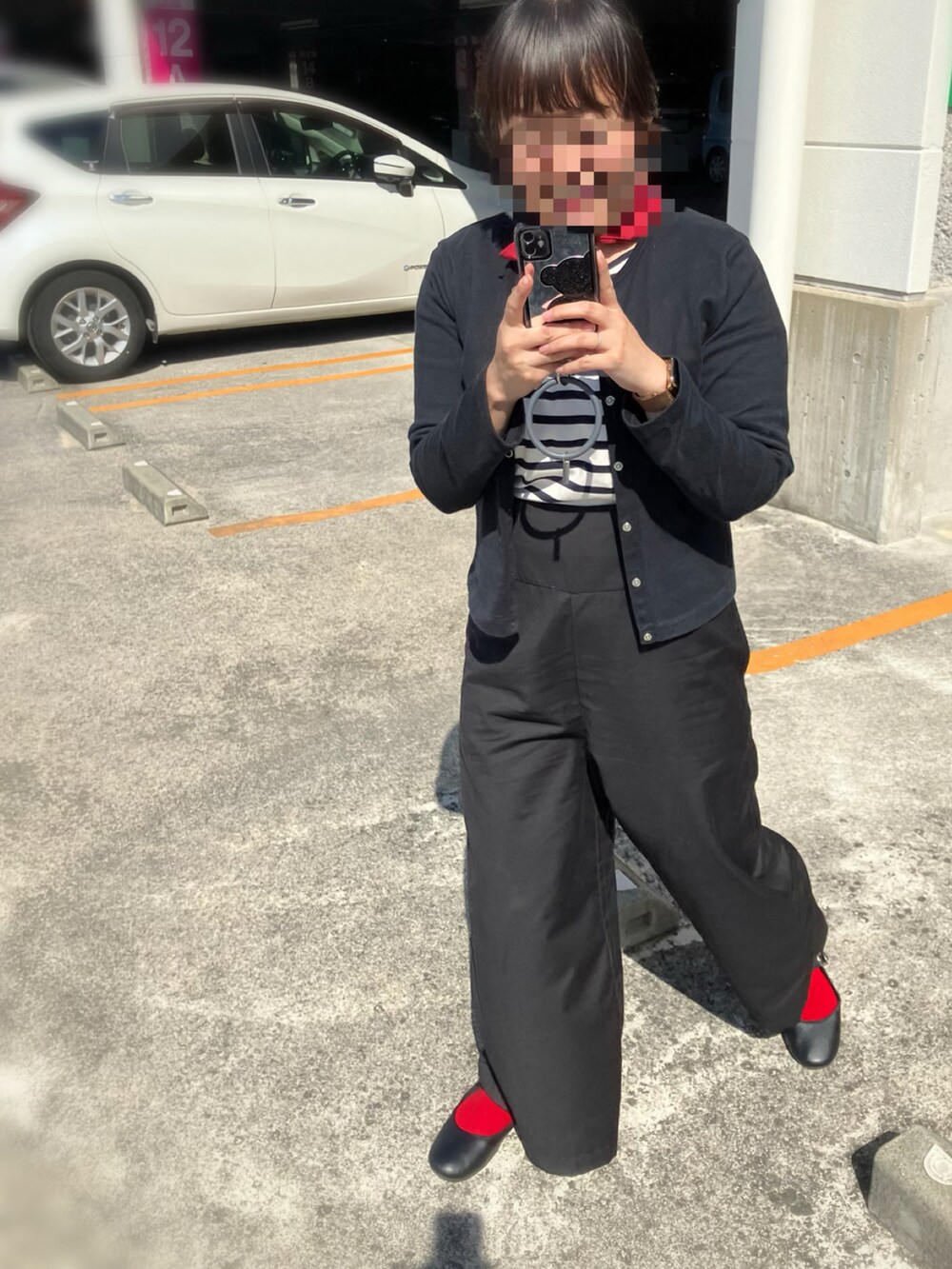 ベージュ系のポンチョ、ブラック系のカーディガン/ボレロ、ホワイト系のトップスを着用したレディースの春コーディネートの2枚目の写真