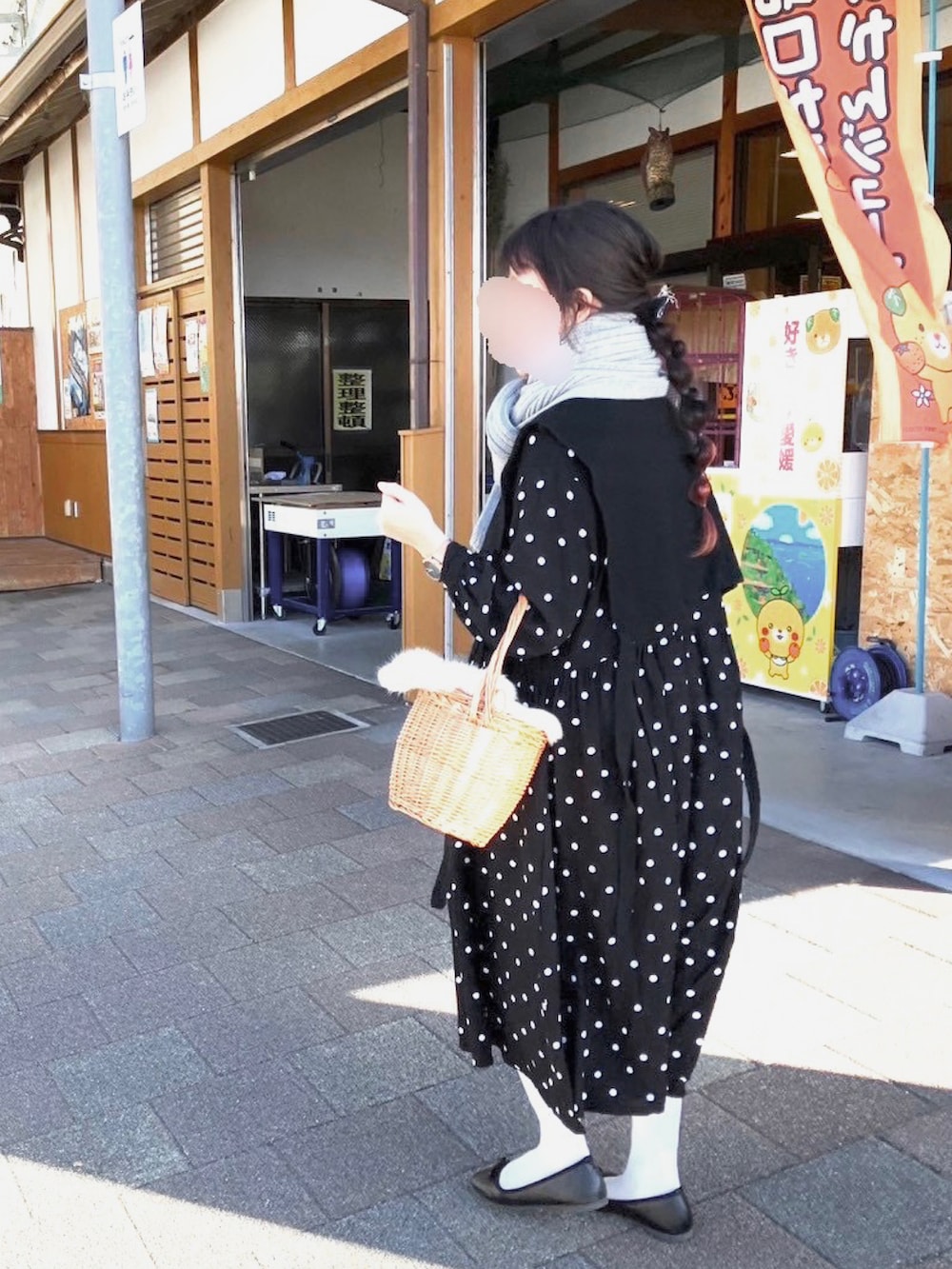 ブラウン系のかごバッグ、ブラック系のノーカラーコート、ブラック系のベストを着用したレディースの冬コーディネートの2枚目の写真