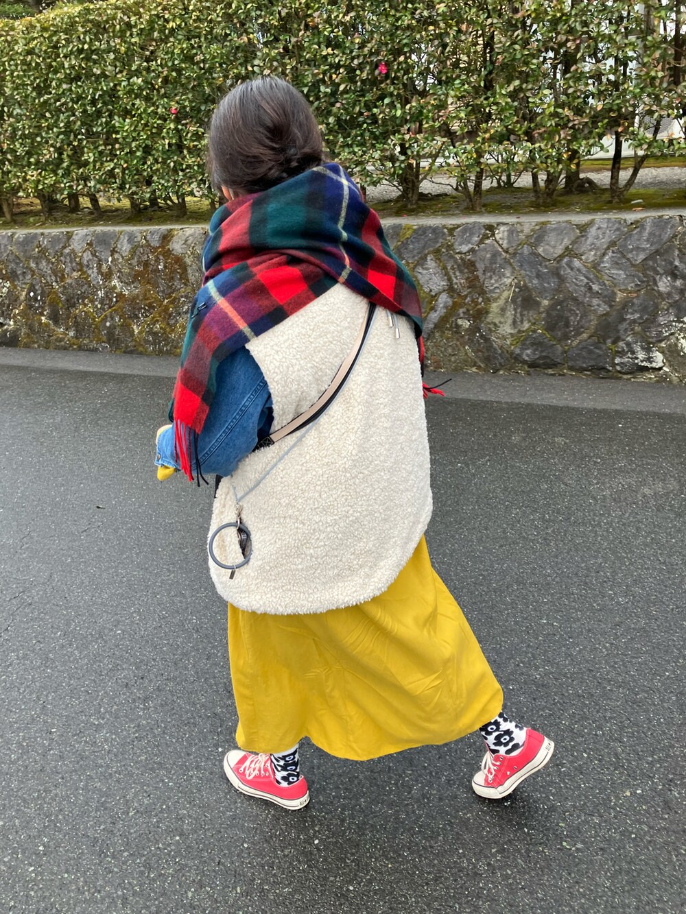 ホワイト系のベスト、イエロー系のワンピース、レッド系のスニーカーを着用したレディースの冬コーディネートの2枚目の写真