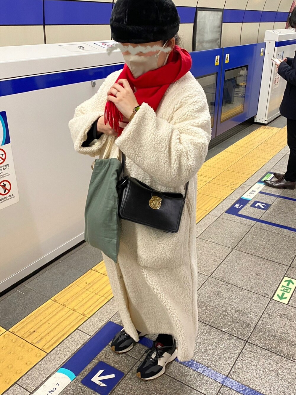 ホワイト系のノーカラーコート、ブラック系のショルダーバッグ、ブラック系のニット/セーターを着用したレディースの冬コーディネートの2枚目の写真