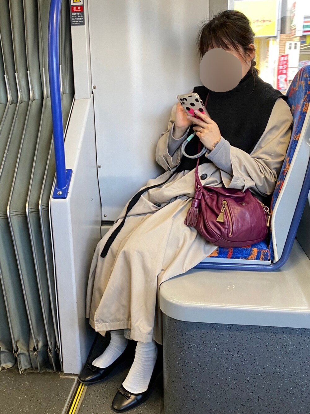 ブラック系のベスト、パープル系のショルダーバッグ、ベージュ系のトレンチコートを着用したレディースの冬コーディネートの2枚目の写真