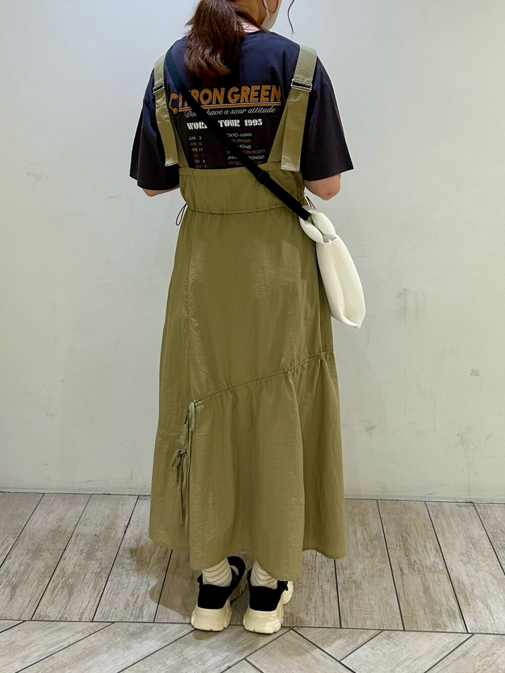 ブラック系のTシャツ/カットソー、ベージュ系のジャンパースカート、ホワイト系のハンドバッグを着用したレディースの夏コーディネートの3枚目の写真