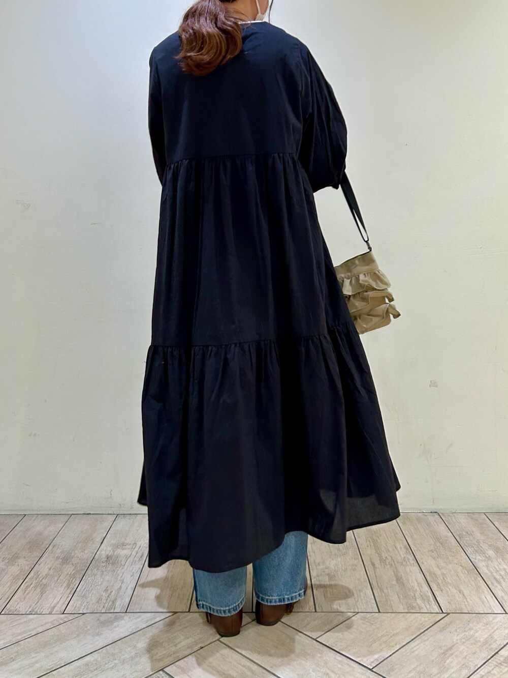 ブラック系のワンピース、ベージュ系のショルダーバッグ、ブルー系のデニムパンツを着用したレディースの冬コーディネートの3枚目の写真