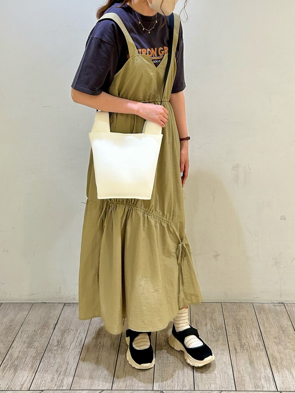 ブラック系のTシャツ/カットソー、ベージュ系のジャンパースカート、ホワイト系のハンドバッグを着用したレディースの夏コーディネートの4枚目の写真