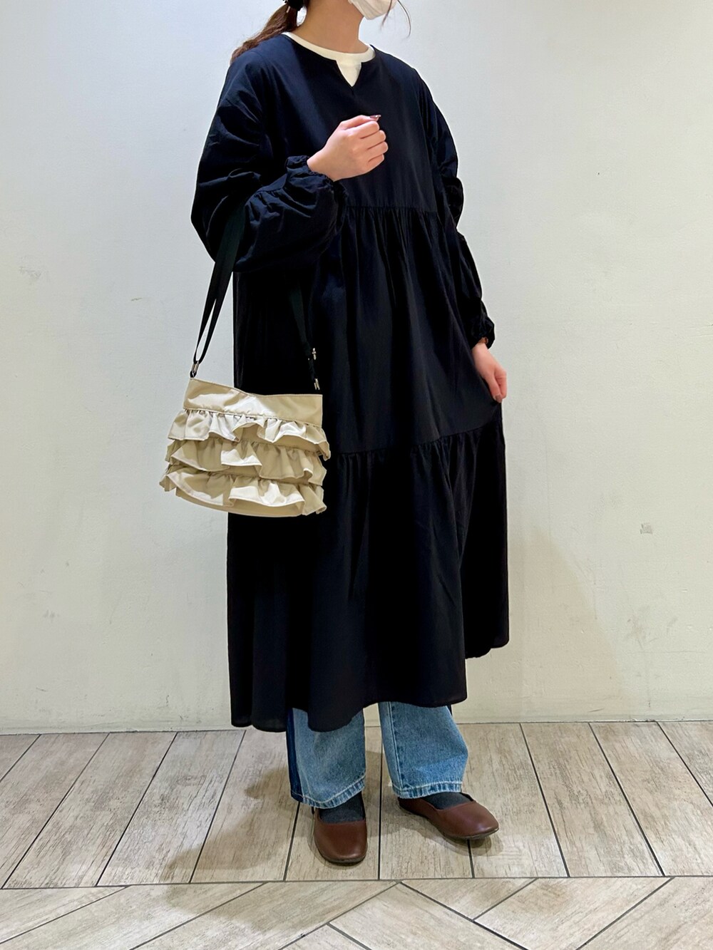 ブラック系のワンピース、ベージュ系のショルダーバッグ、ブルー系のデニムパンツを着用したレディースの冬コーディネートの5枚目の写真