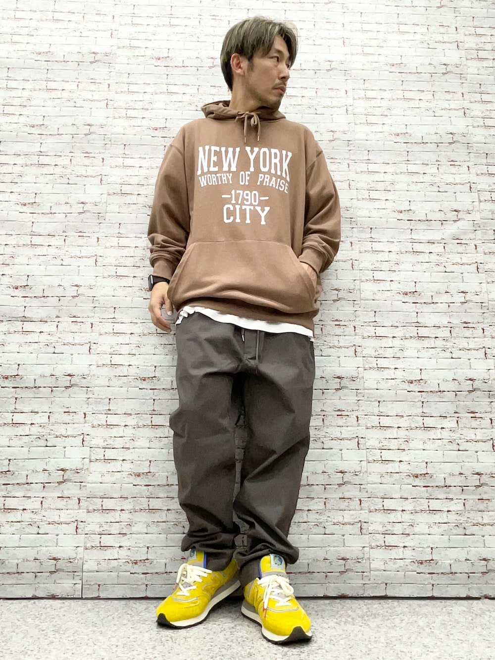 ブラウン系のパーカー、グレー系のチノパンツ、イエロー系のスニーカーを着用したメンズの秋コーディネートの3枚目の写真