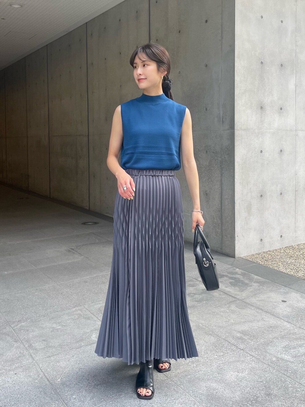 グレー系のスカート、ブルー系のニット/セーターを着用したレディースの夏コーディネートの2枚目の写真