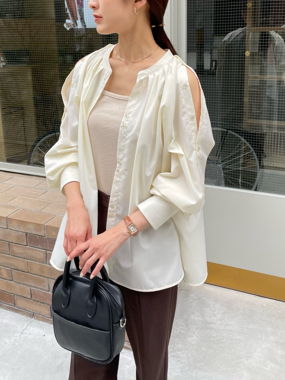 ホワイト系のシャツ/ブラウス、ブラウン系のスラックス、シルバー系のネックレスを着用したレディースの夏コーディネートの2枚目の写真