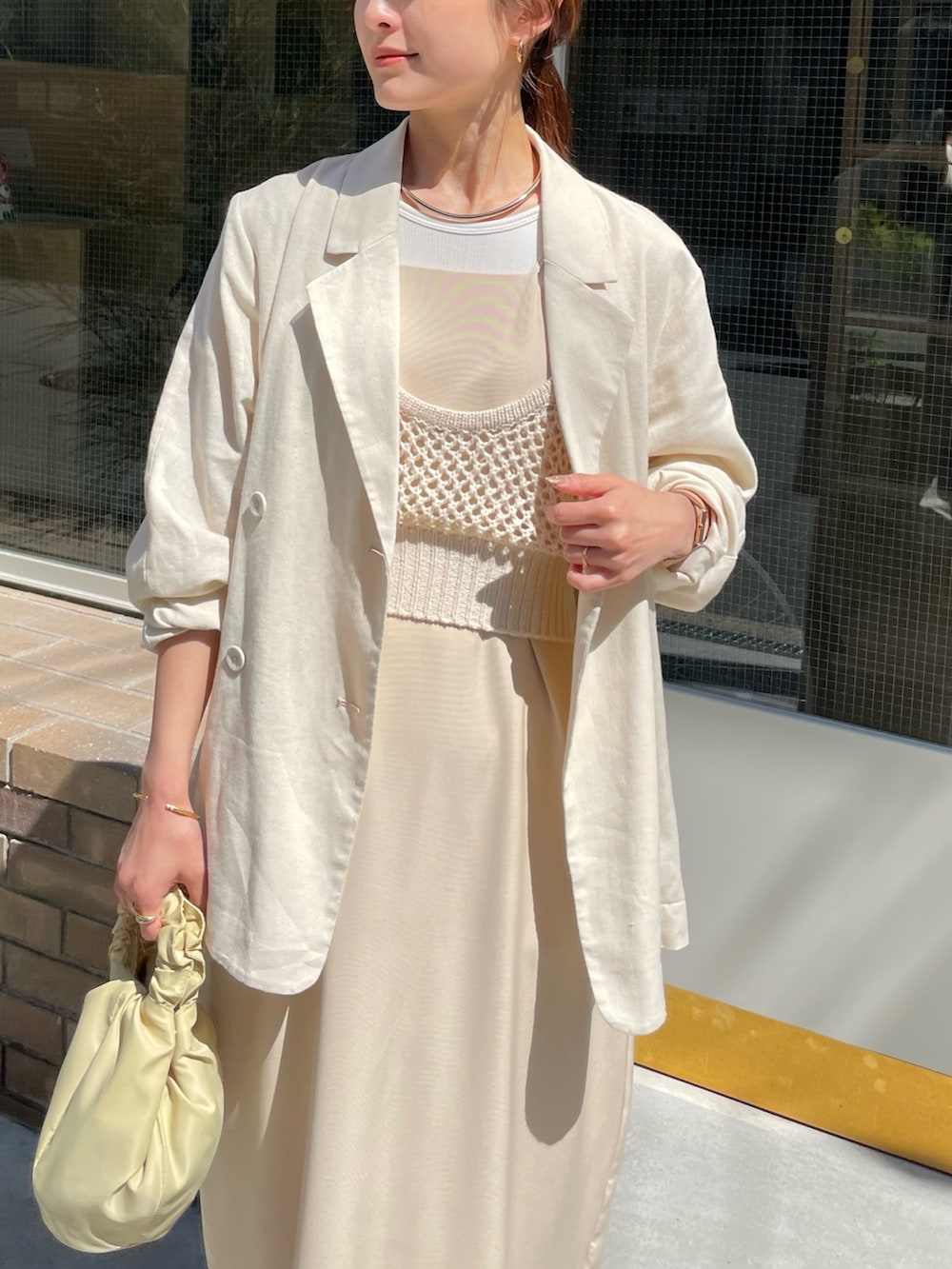 ホワイト系のベスト、ホワイト系のドレス、ベージュ系のバッグを着用したレディースの春コーディネートの2枚目の写真