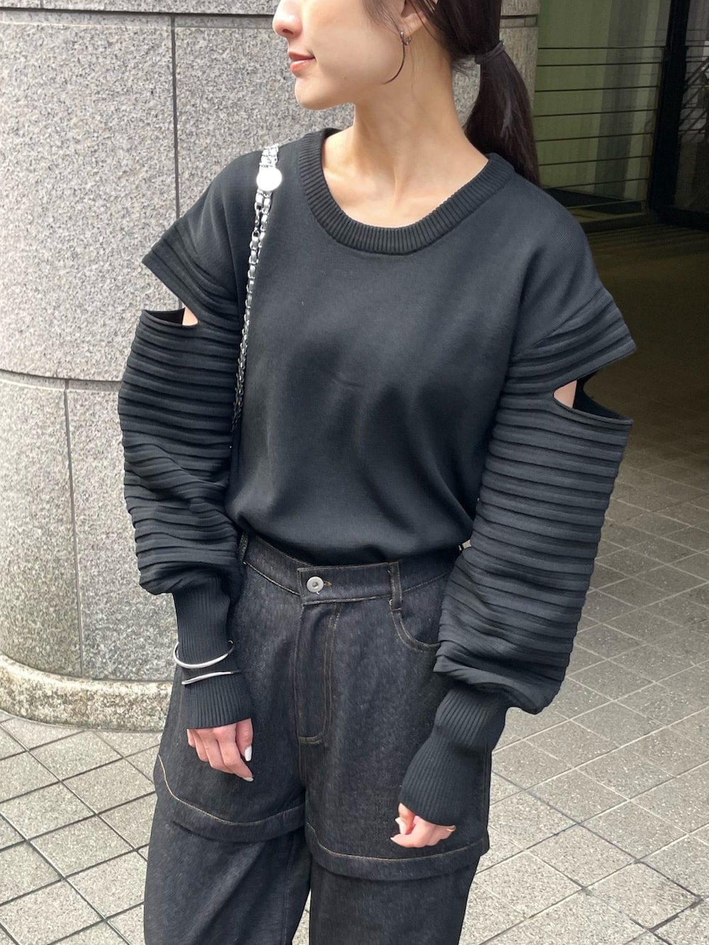 ブラック系のニット/セーター、ブラック系のデニムパンツを着用したレディースの春コーディネートの3枚目の写真