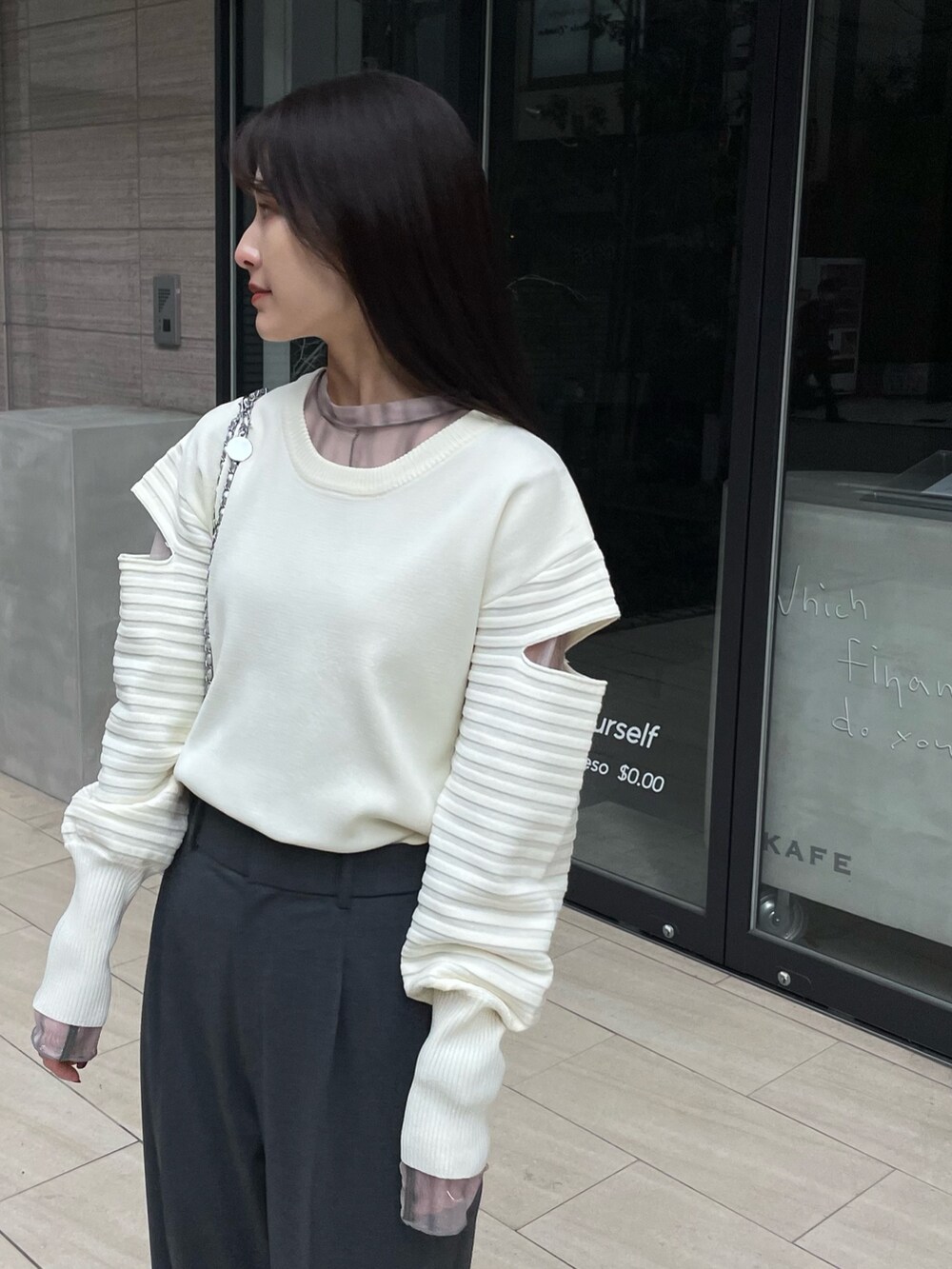 ホワイト系のニット/セーター、ベージュ系のTシャツ/カットソー、グレー系のパンツを着用したレディースの春コーディネートの2枚目の写真