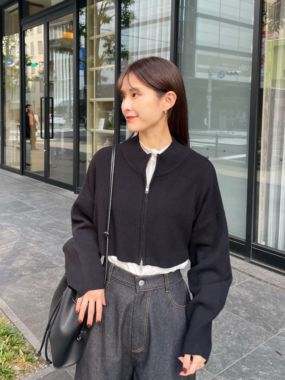 ブラック系のブルゾン、ホワイト系のTシャツ/カットソー、ブラック系のデニムパンツを着用したレディースの秋コーディネートの2枚目の写真