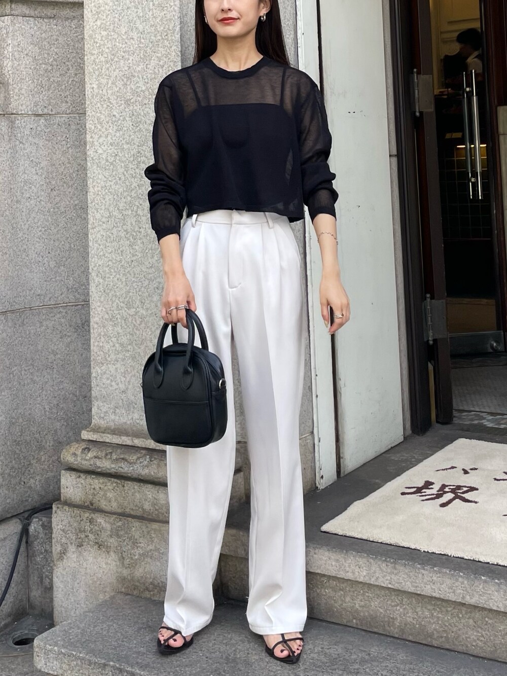 ブラック系のニット/セーター、ホワイト系のその他パンツを着用したレディースの夏コーディネートの3枚目の写真
