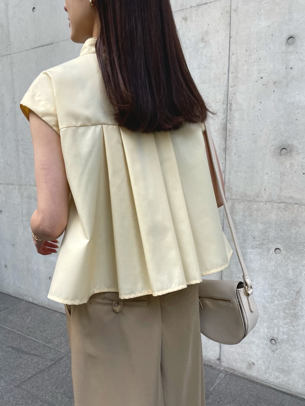 イエロー系のシャツ/ブラウス、ベージュ系のスカート、ベージュ系のサンダルを着用したレディースの春コーディネートの2枚目の写真