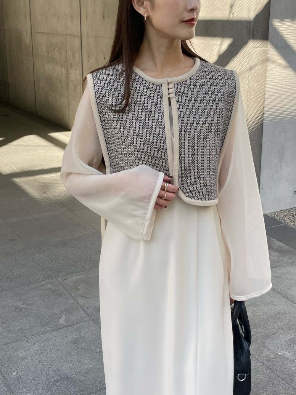 ホワイト系のベスト、ホワイト系のドレス、ゴールド系のリングを着用したレディースの秋コーディネートの2枚目の写真