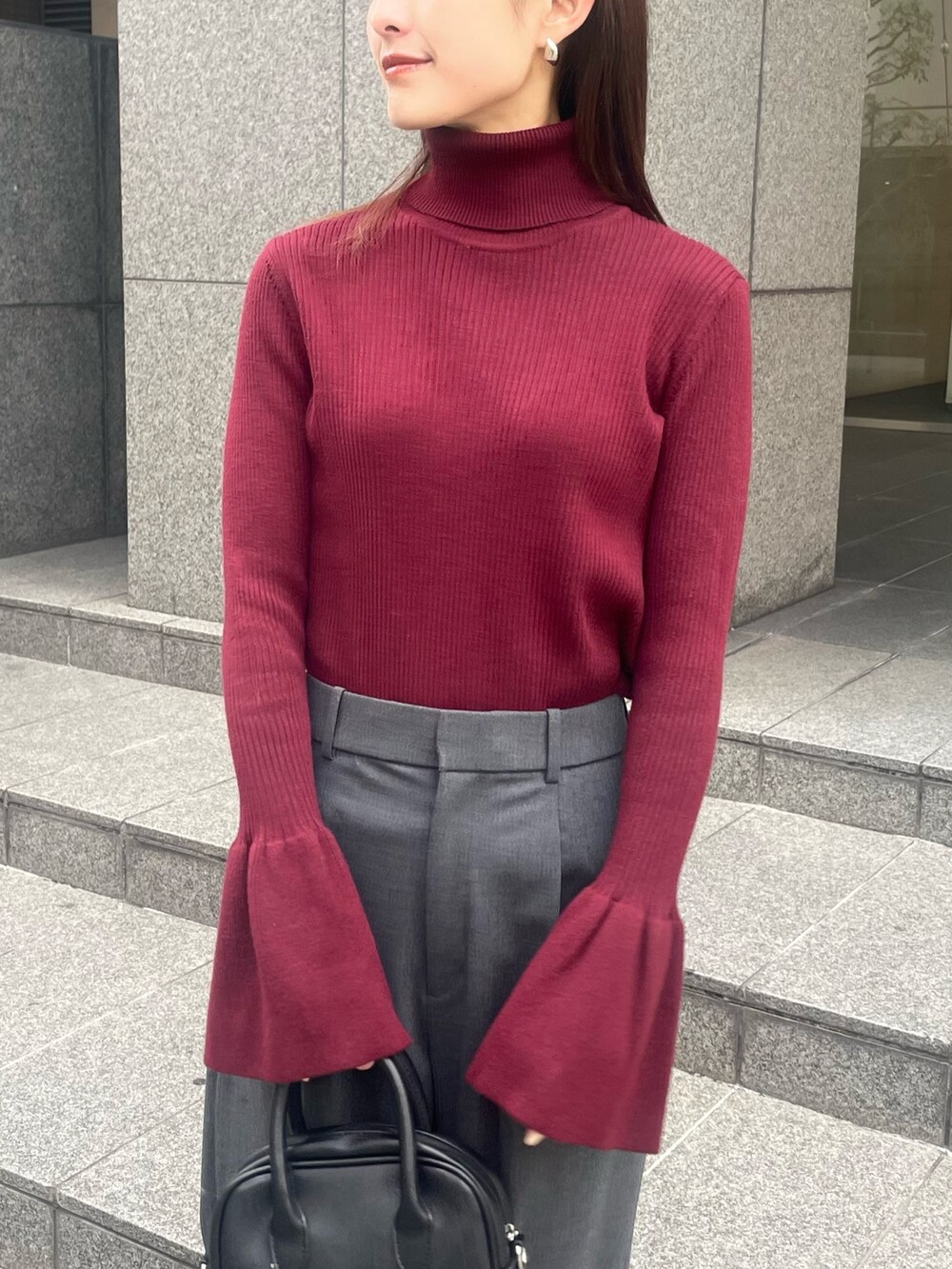 レッド系のニット/セーター、グレー系のパンツ、ブラック系のデニムジャケットを着用したレディースの秋コーディネートの3枚目の写真