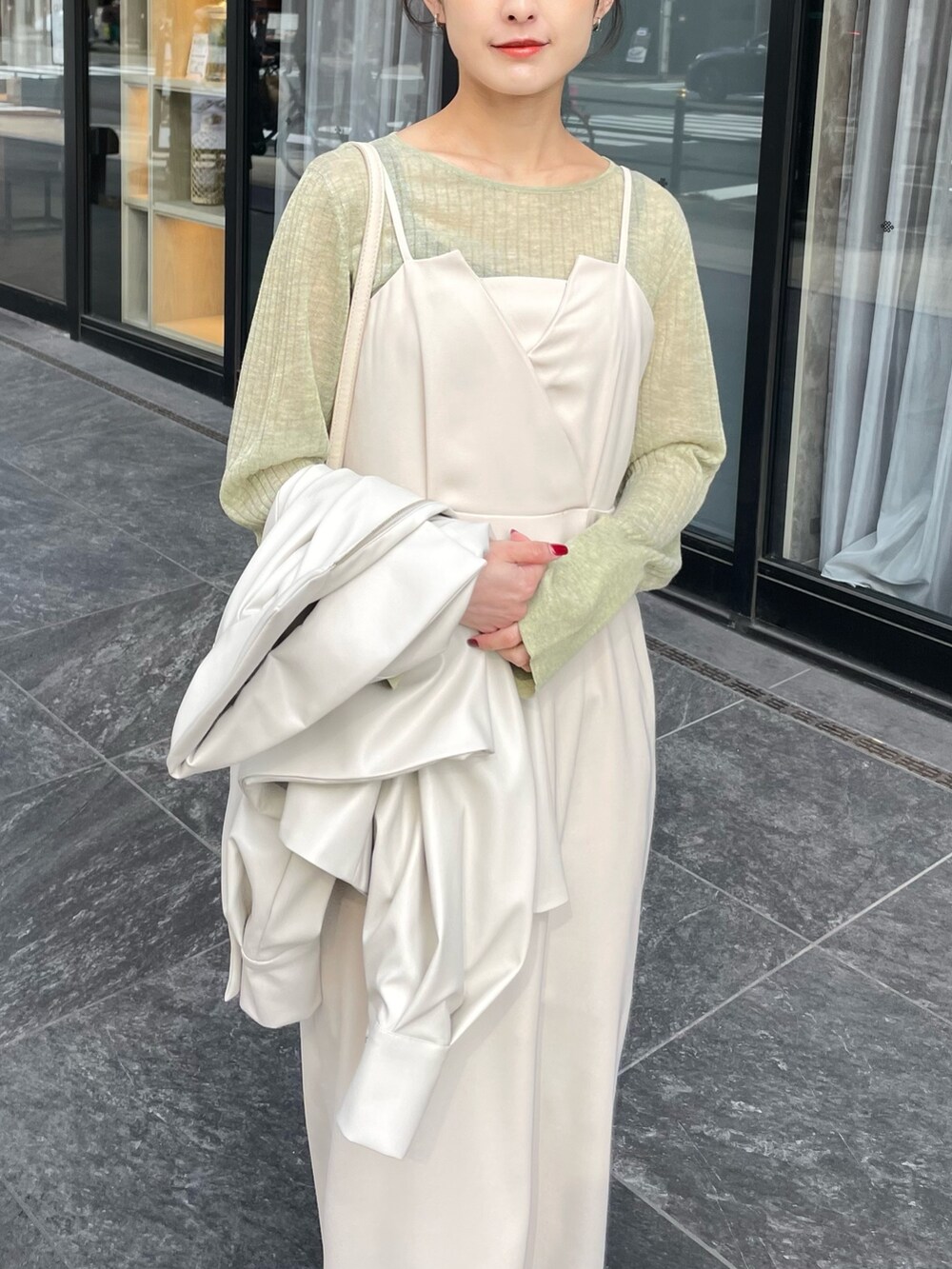 グリーン系のニット/セーター、ホワイト系のブルゾン、ホワイト系のドレスを着用したレディースの春コーディネートの2枚目の写真