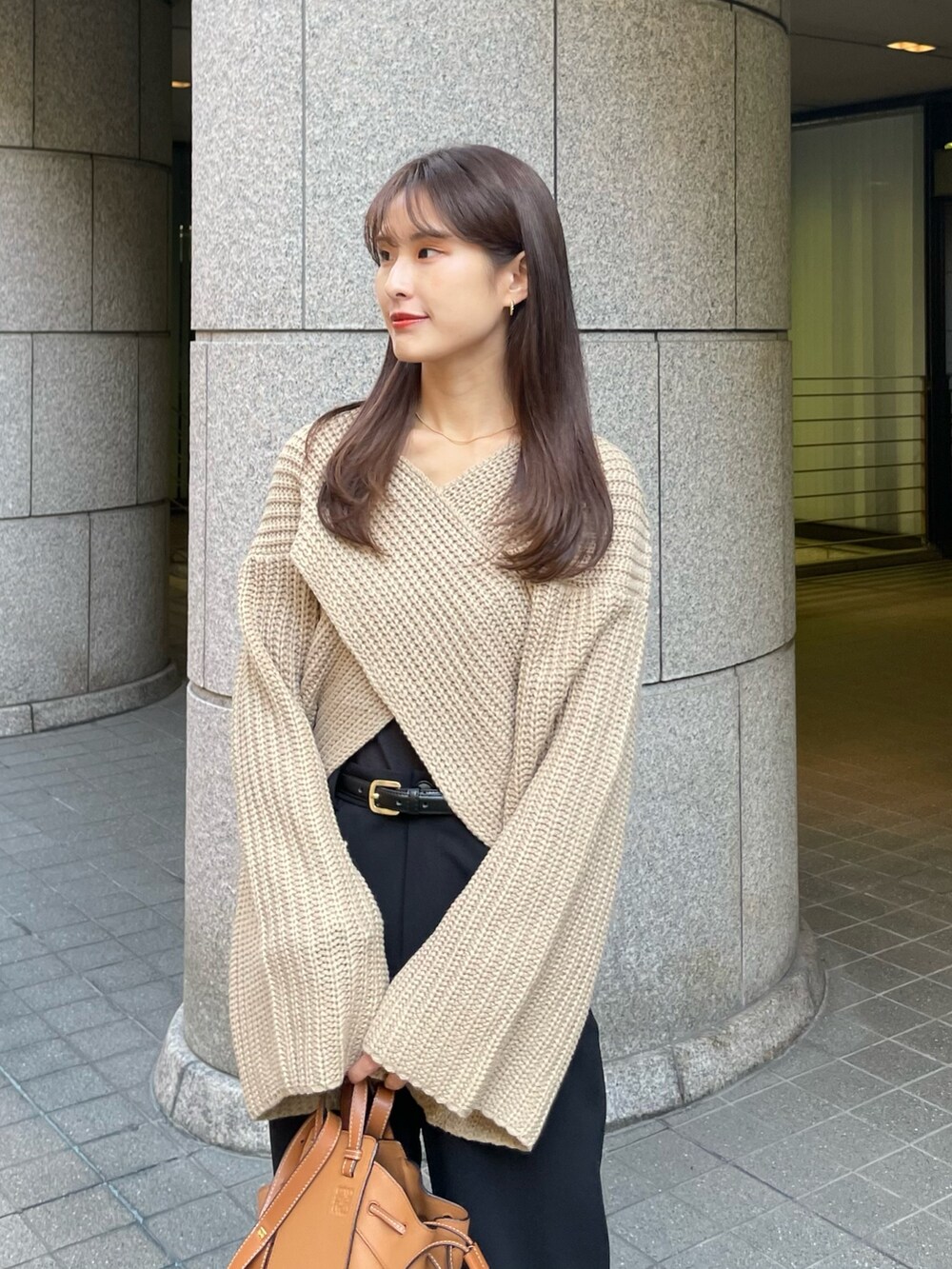 ベージュ系のニット/セーター、ブラウン系のバッグ、ブラック系のブーツを着用したレディースの秋コーディネートの2枚目の写真