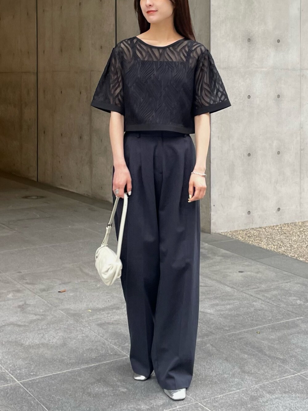 ブラック系のシャツ/ブラウス、ブルー系のスラックスを着用したレディースの春コーディネートの2枚目の写真