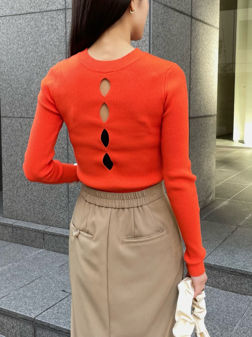 オレンジ系のニット/セーター、ベージュ系のスカートを着用したレディースの冬コーディネートの3枚目の写真