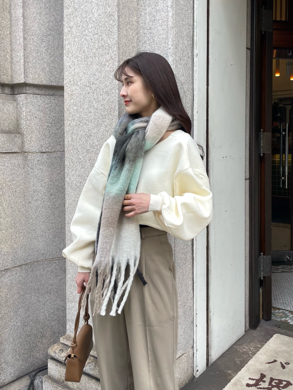 ブラウン系のブーツ、ブラウン系のハンドバッグ、ホワイト系のニット/セーターを着用したレディースの冬コーディネートの2枚目の写真