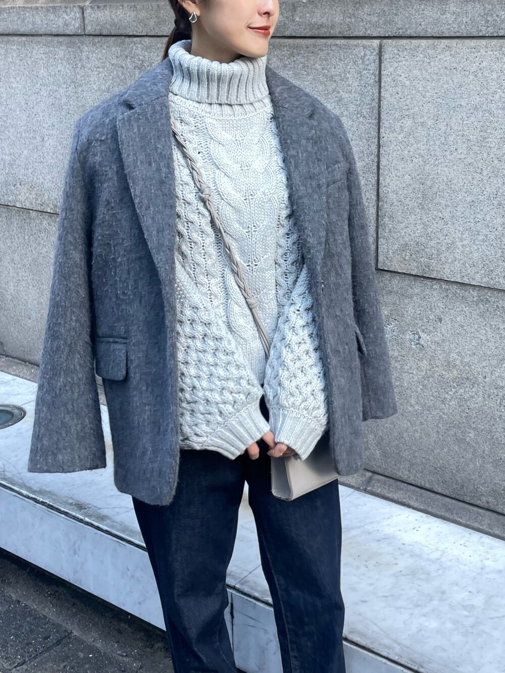 グレー系のニット/セーター、ブルー系のデニムパンツを着用したレディースの秋コーディネートの2枚目の写真