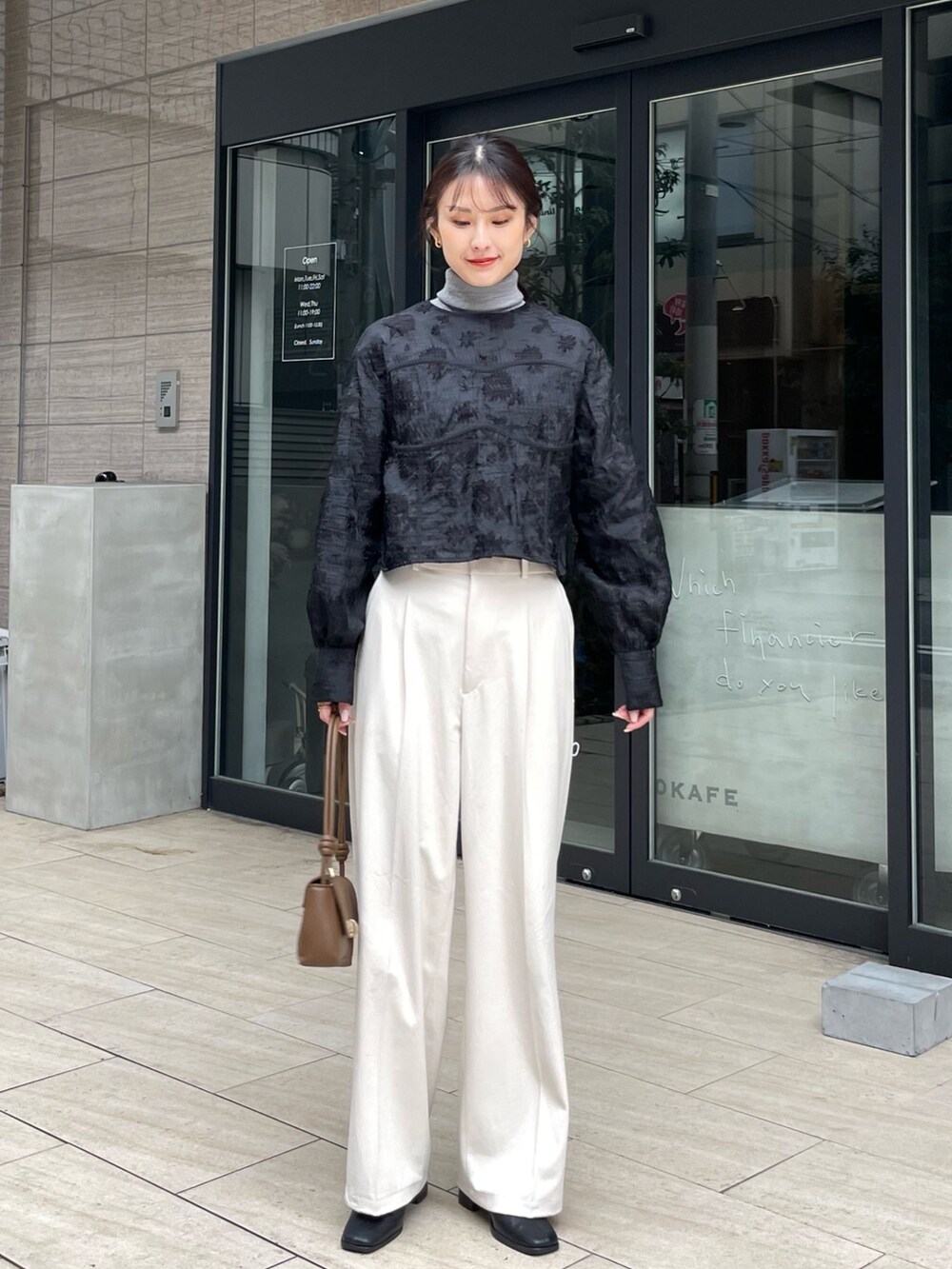 ブラック系のシャツ/ブラウス、ホワイト系のパンツ、ブラウン系のハンドバッグを着用したレディースの冬コーディネートの2枚目の写真