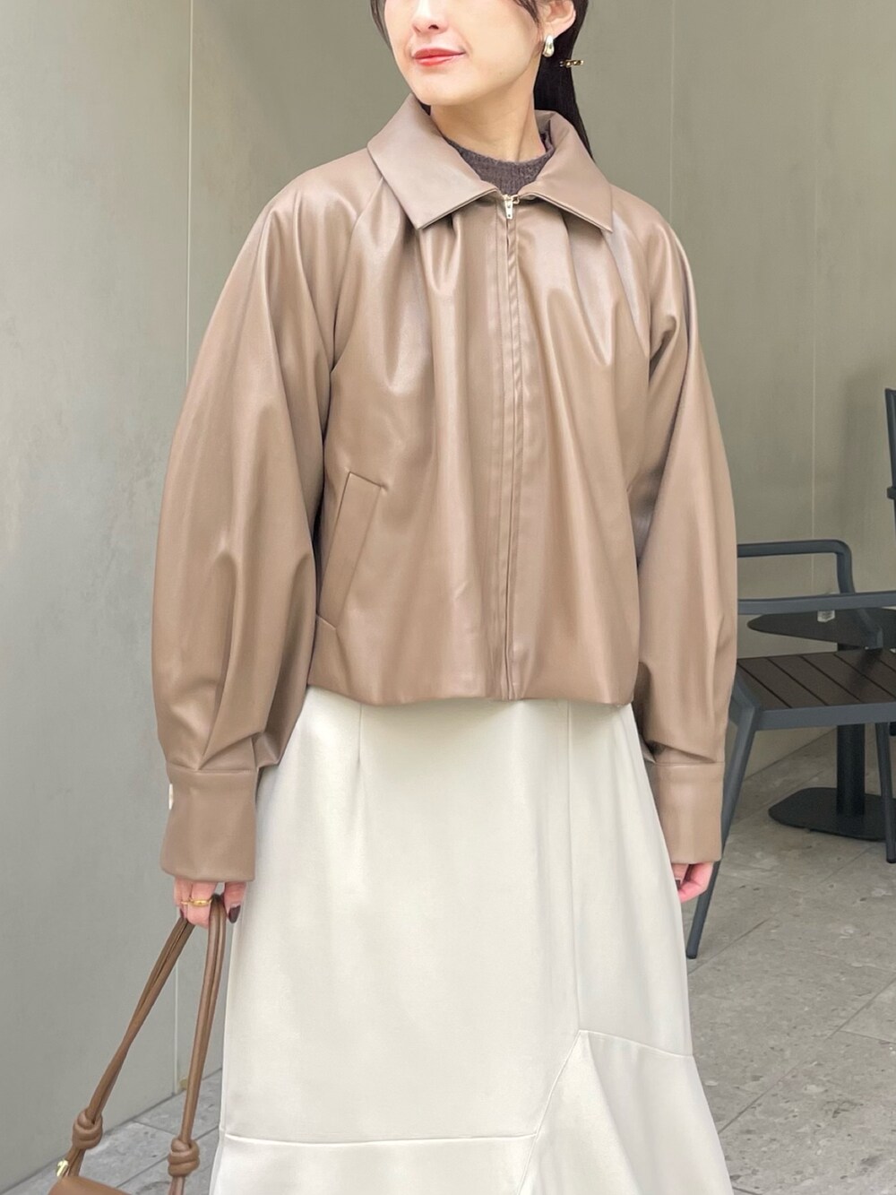 ベージュ系のブルゾン、ホワイト系のスカートを着用したレディースの冬コーディネートの2枚目の写真