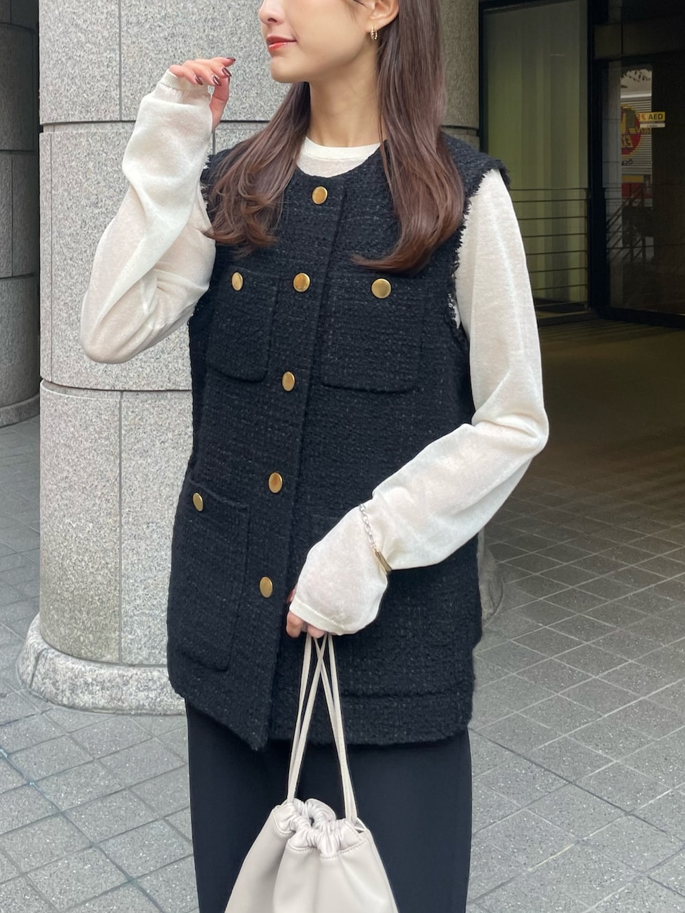 ブラック系のノーカラージャケット、ホワイト系のニット/セーターを着用したレディースの秋コーディネートの2枚目の写真